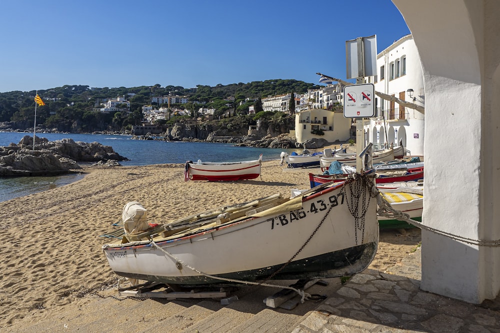 a white boat sitting on top of a sandy beach