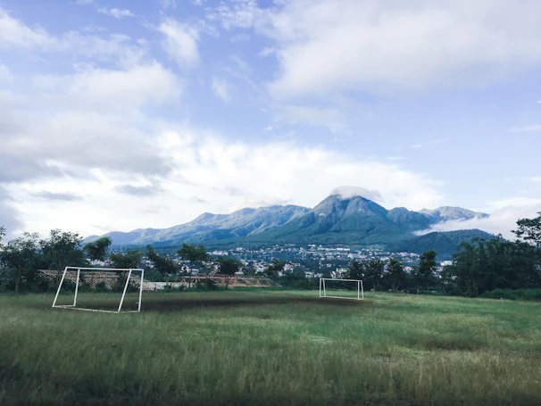 Action shot of players from Rías Baixas F.C. training on a green field with mountains in the background.