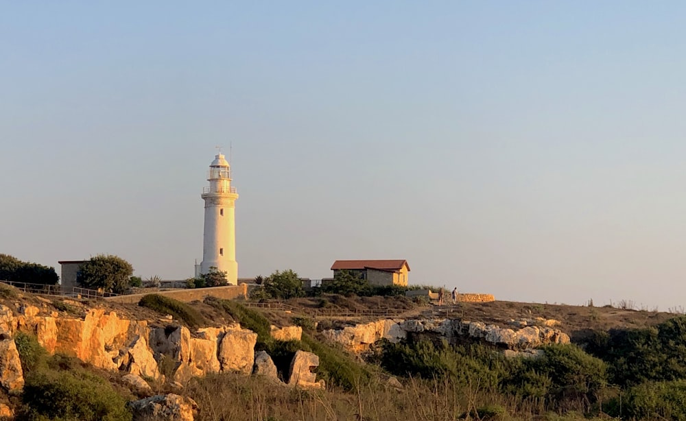 a light house on a hill with trees and bushes