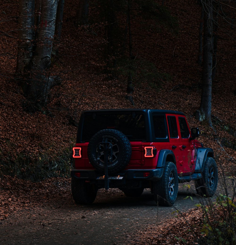 a red jeep driving down a dirt road at night