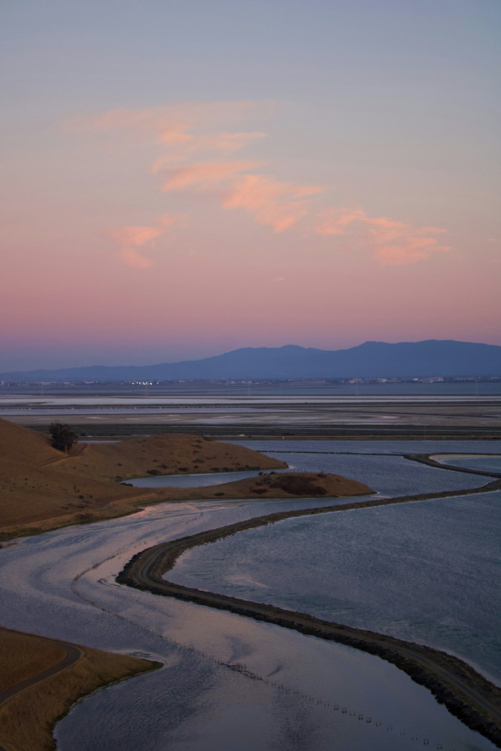 a river running through a dry grass covered field