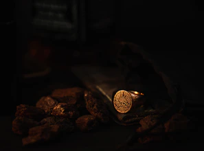 Close-up of a delicate obsidian ring resting on textured volcanic rock under warm natural light
