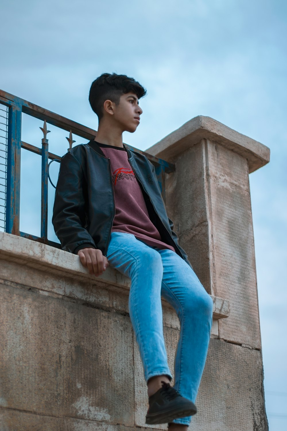 a young man sitting on a ledge of a building