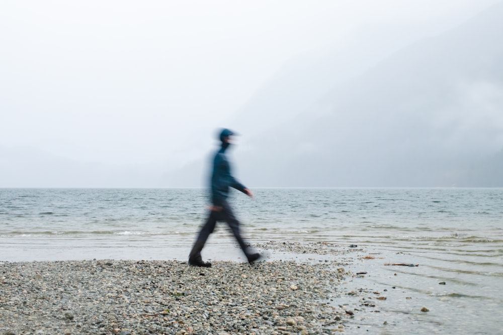 a blurry photo of a man walking on a beach