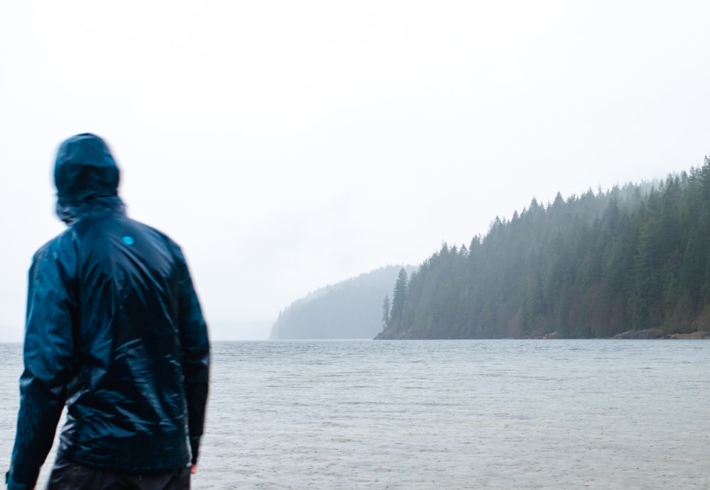 a man standing on a beach next to a body of water