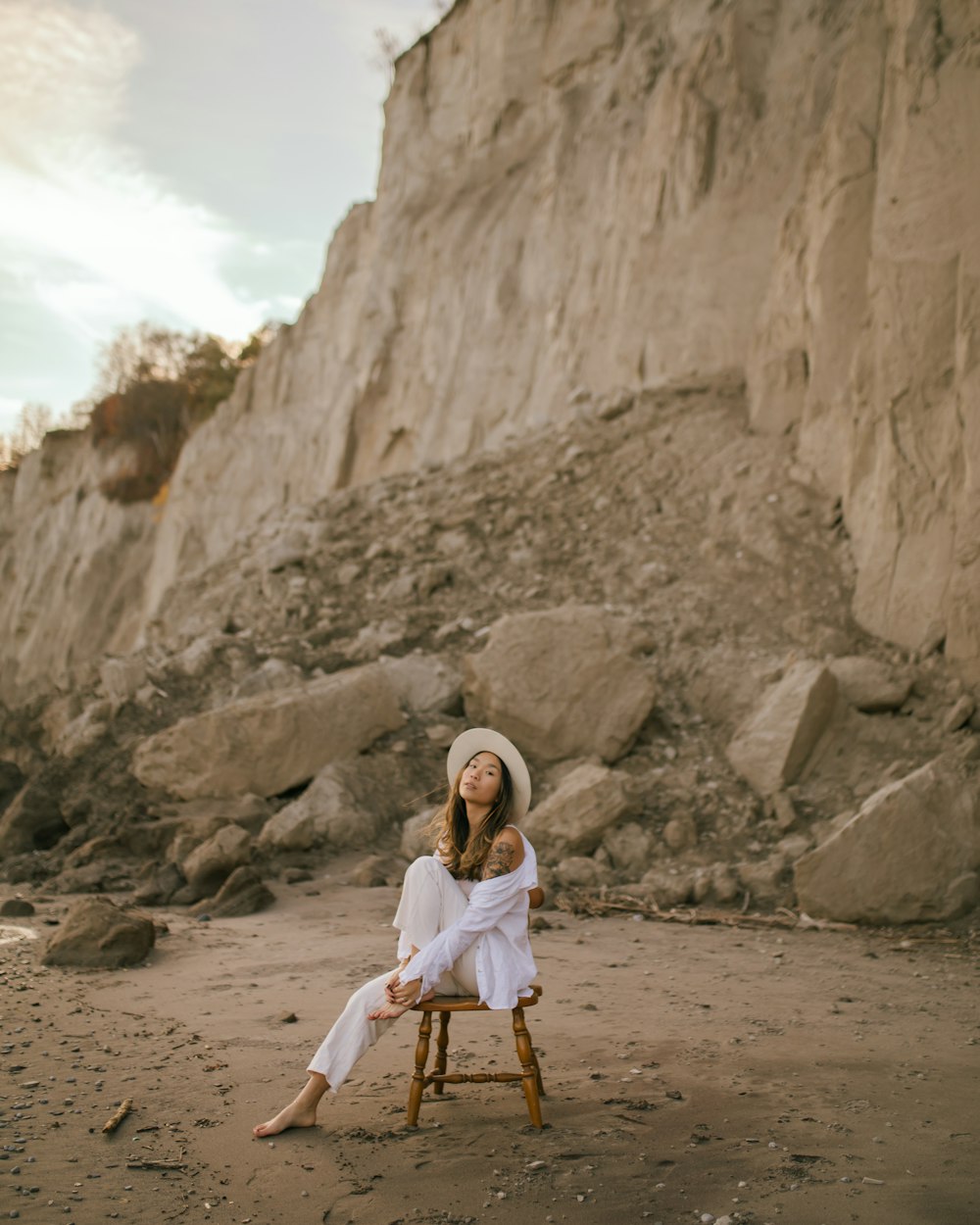 uma mulher sentada em cima de uma cadeira de madeira em uma praia