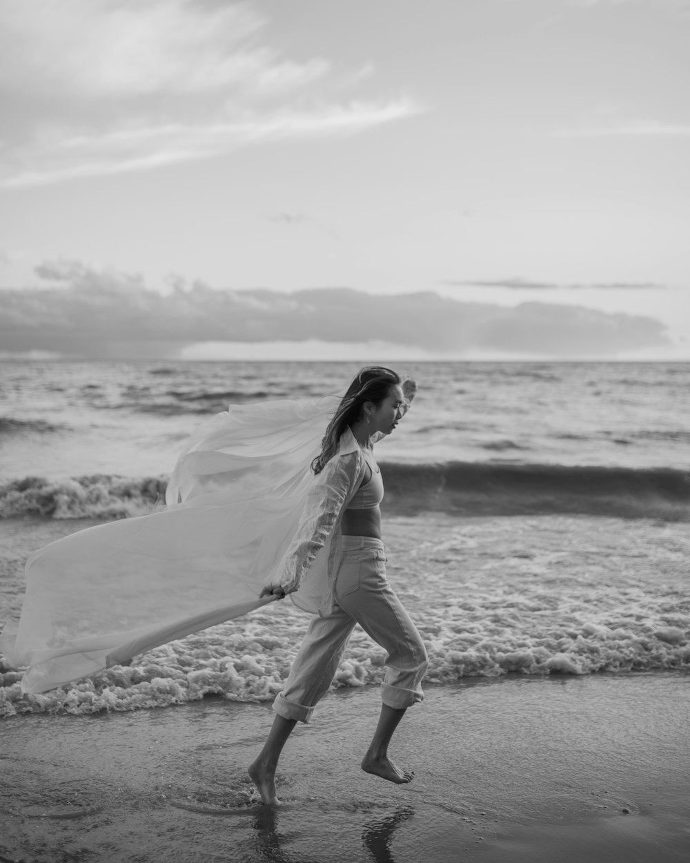 a woman walking on a beach with a veil over her head