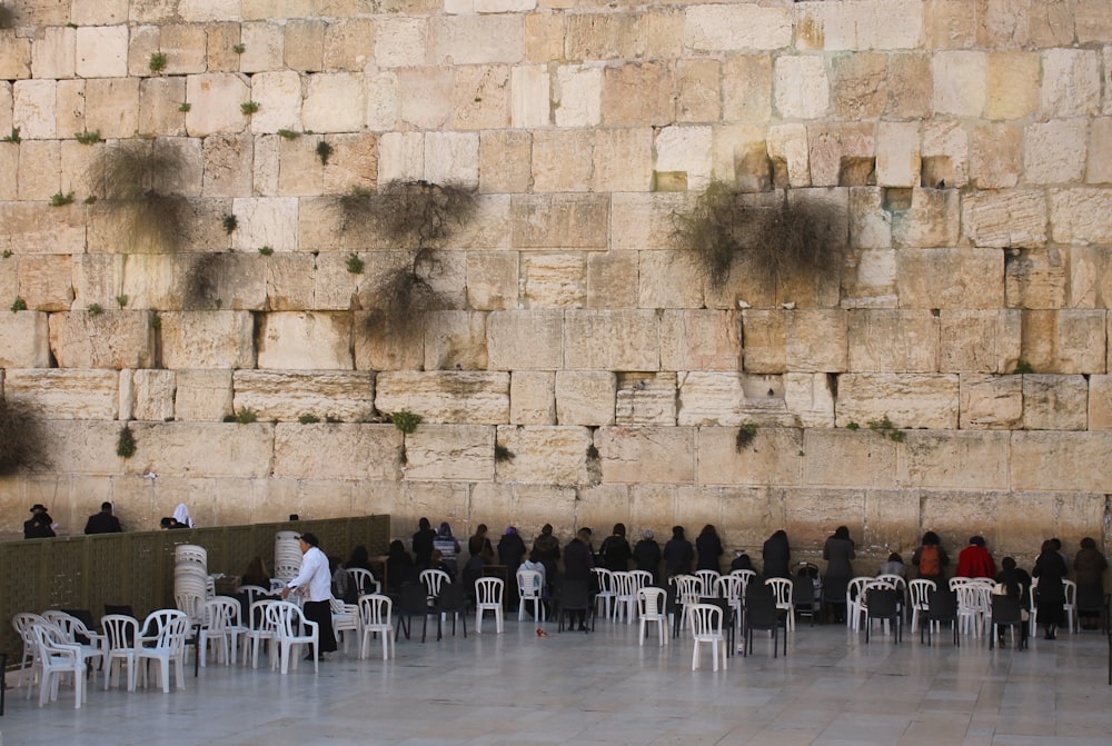 a group of people sitting at tables in front of a wall