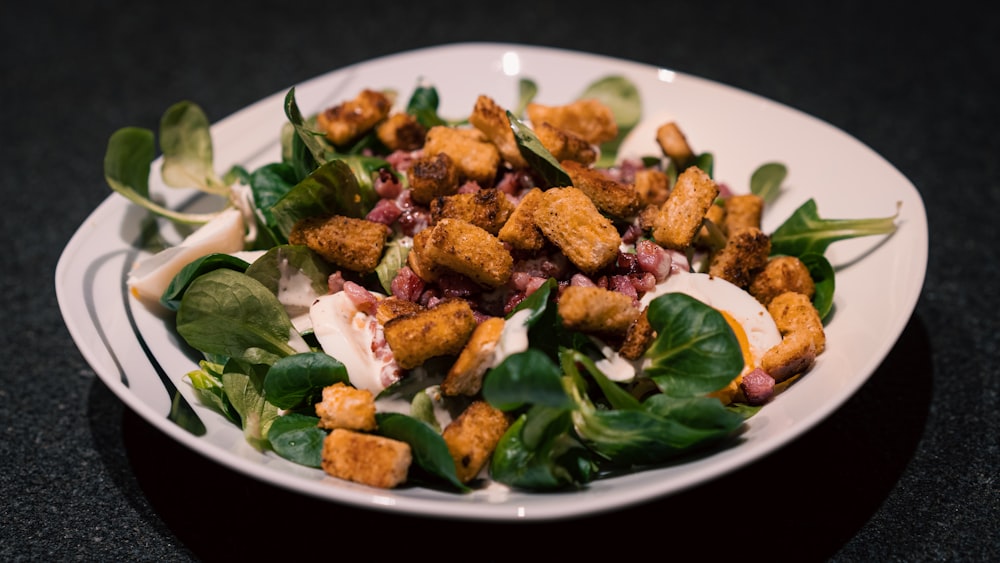 a white plate topped with a salad covered in croutons