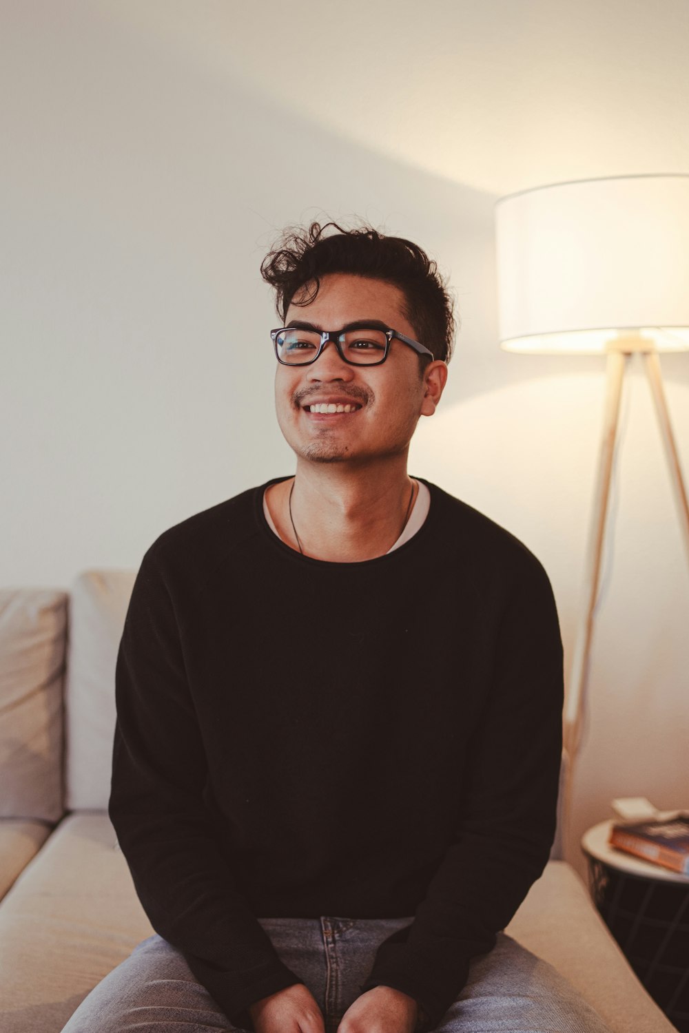 a man sitting on top of a couch next to a lamp