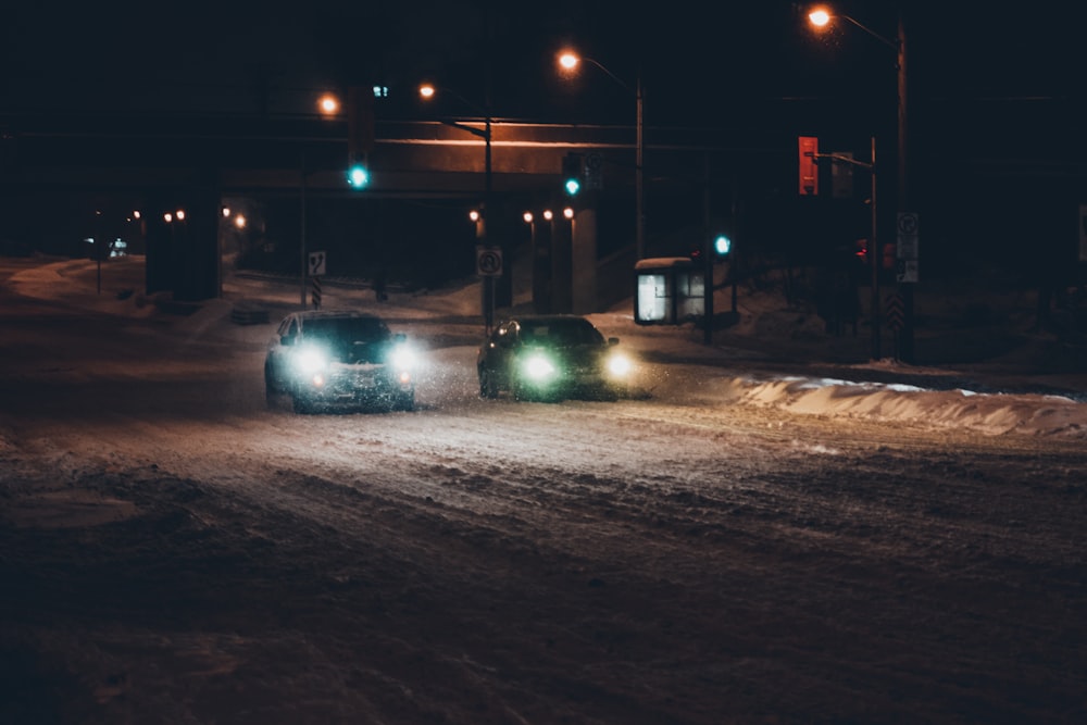 a couple of cars driving down a snow covered road