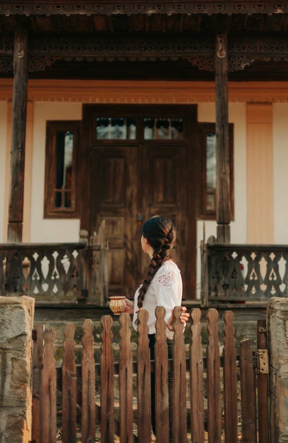 a little girl standing in front of a wooden fence