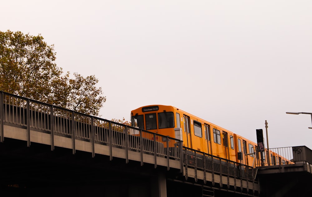 a yellow train traveling over a bridge on a cloudy day