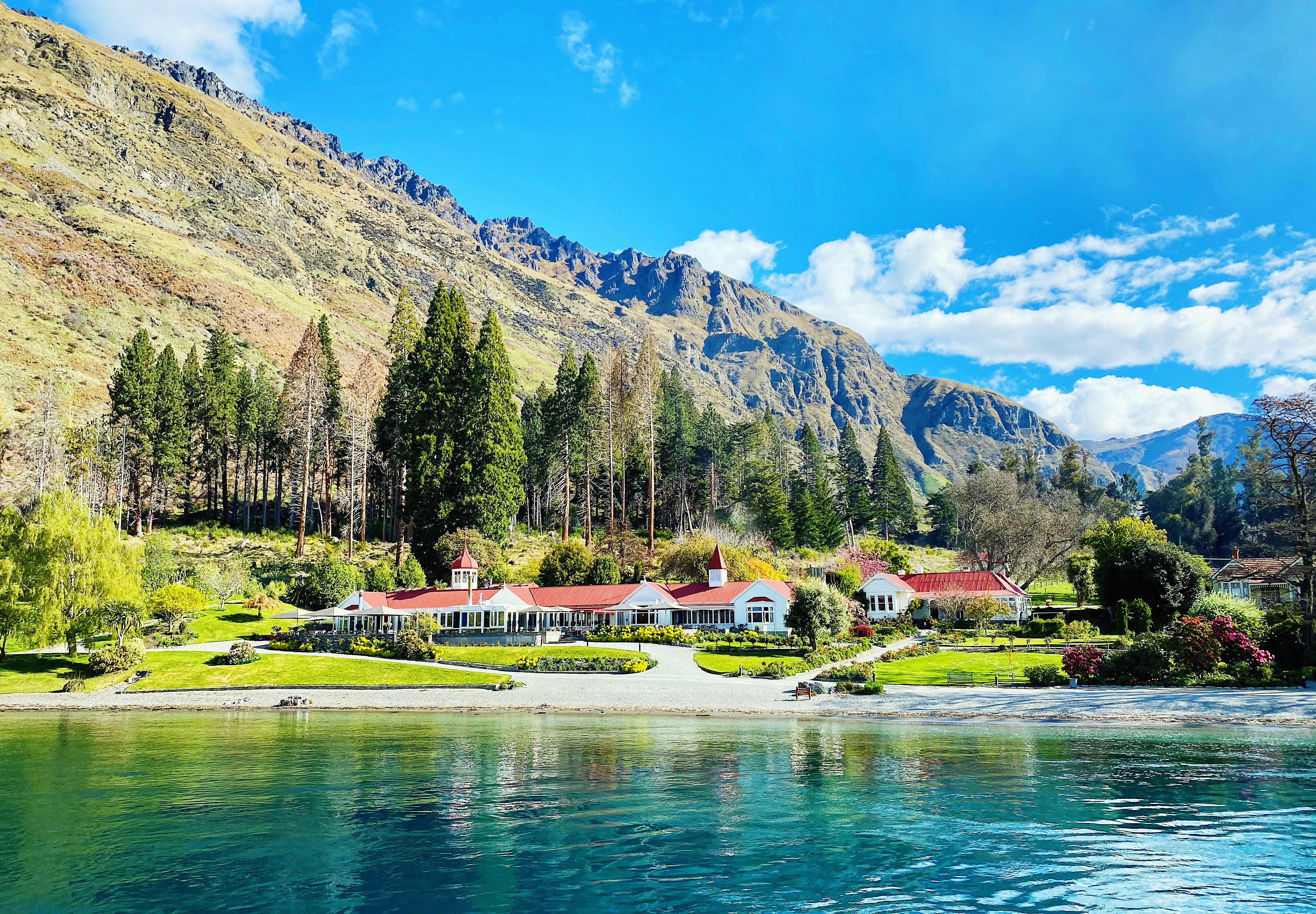a house on the shore of a lake with mountains in the background