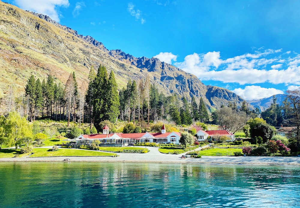 a house on the shore of a lake with mountains in the background