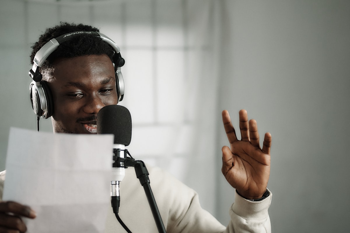 Man wearing headphones holding a microphone in a recording setup
