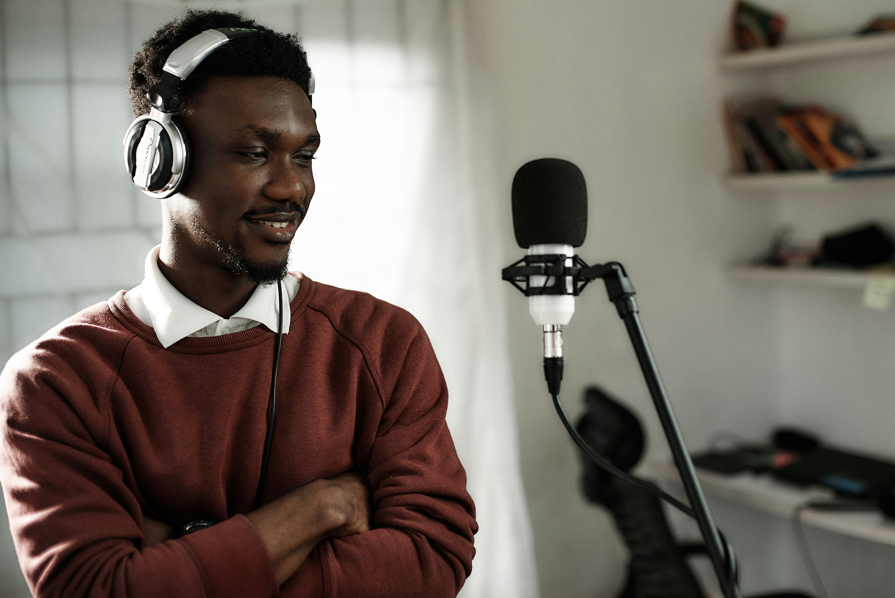 African male voice over artist recording a voice-over script with a condenser and Pioneer exclusive headphones.