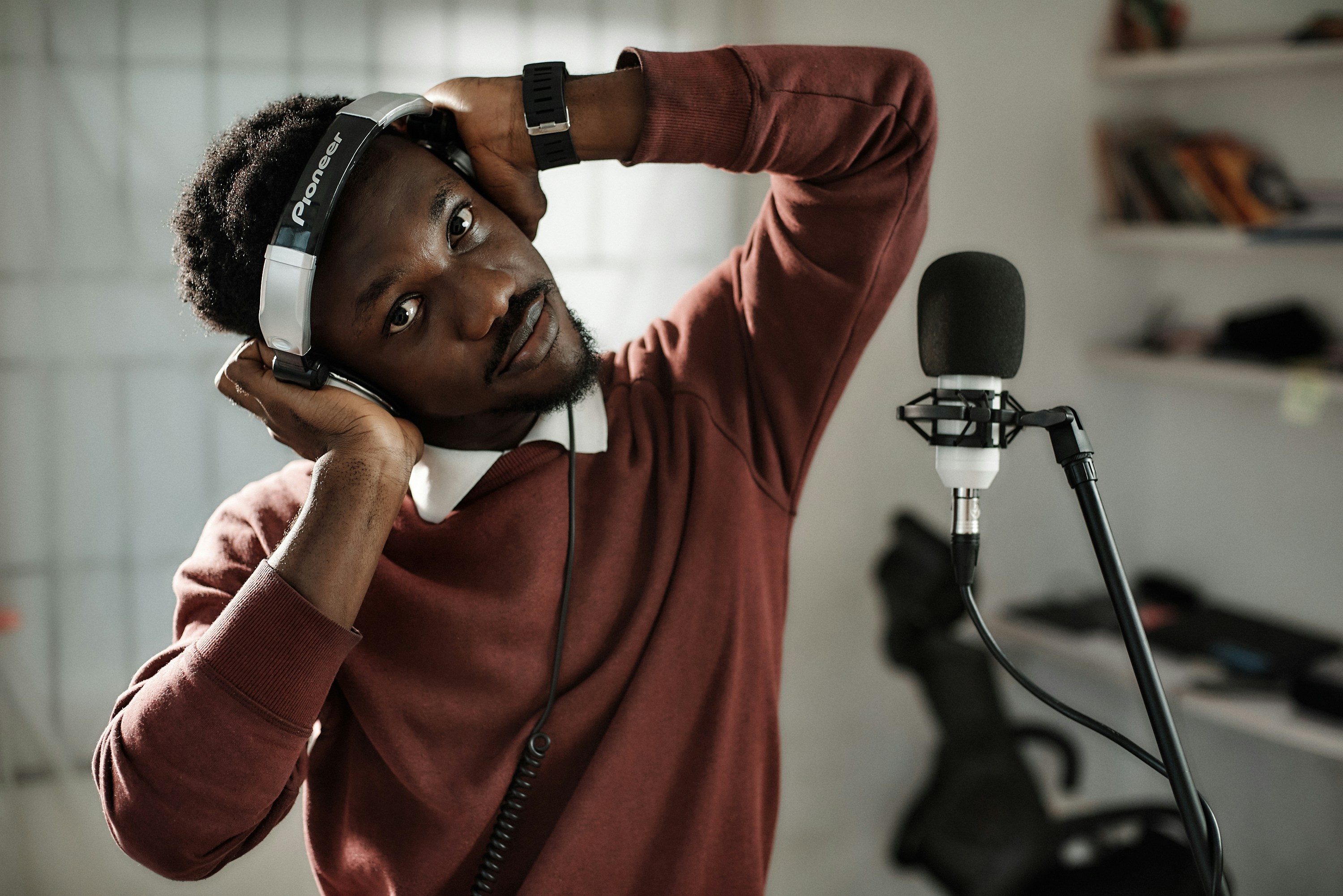 African male voice over artist recording a voice-over script with a condenser and Pioneer exclusive headphones.