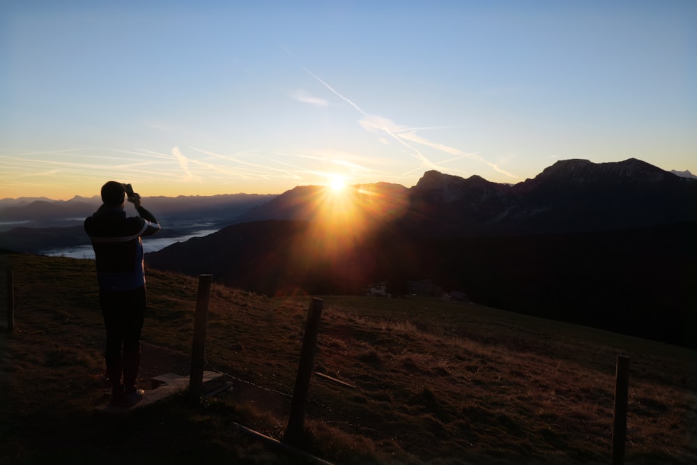 a person taking a picture of the sun setting