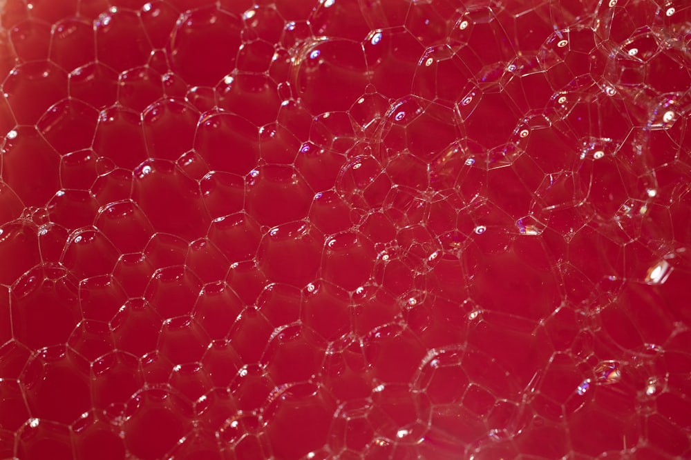 a close up of a red surface with bubbles