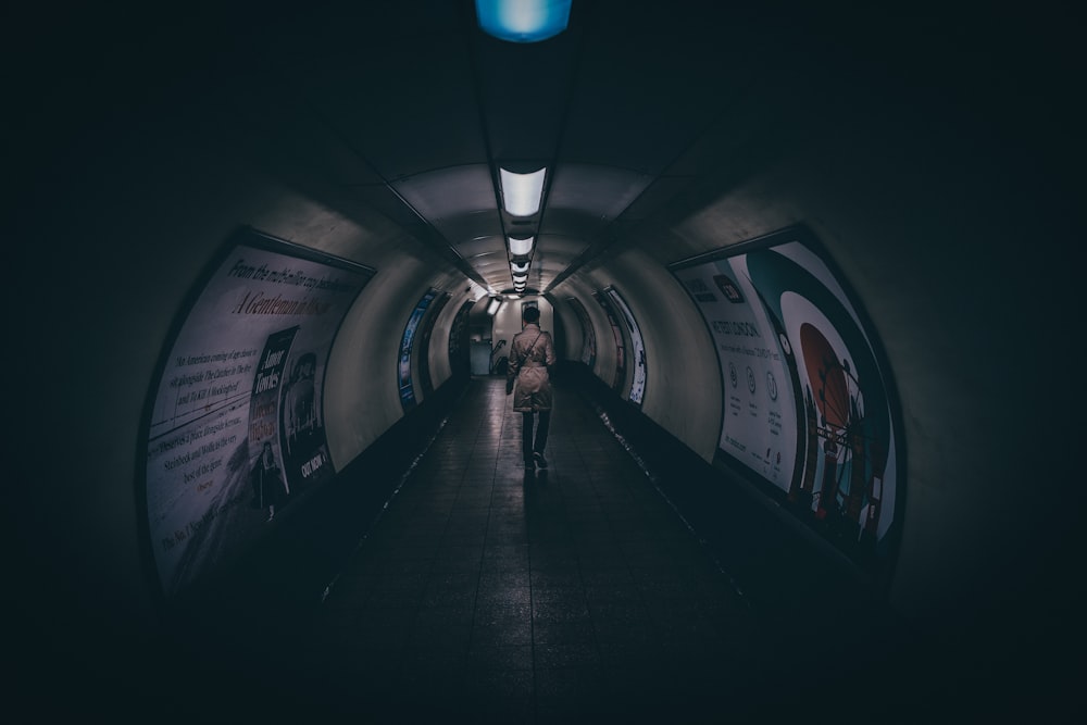 a person walking down a long hallway in the dark