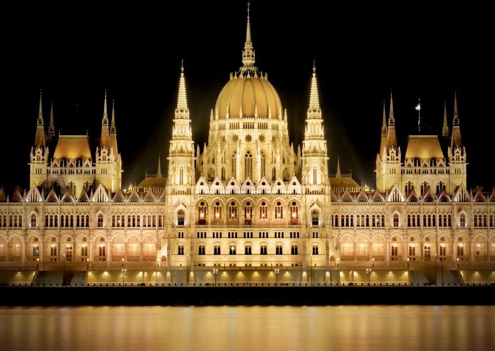 a large building lit up at night next to a body of water