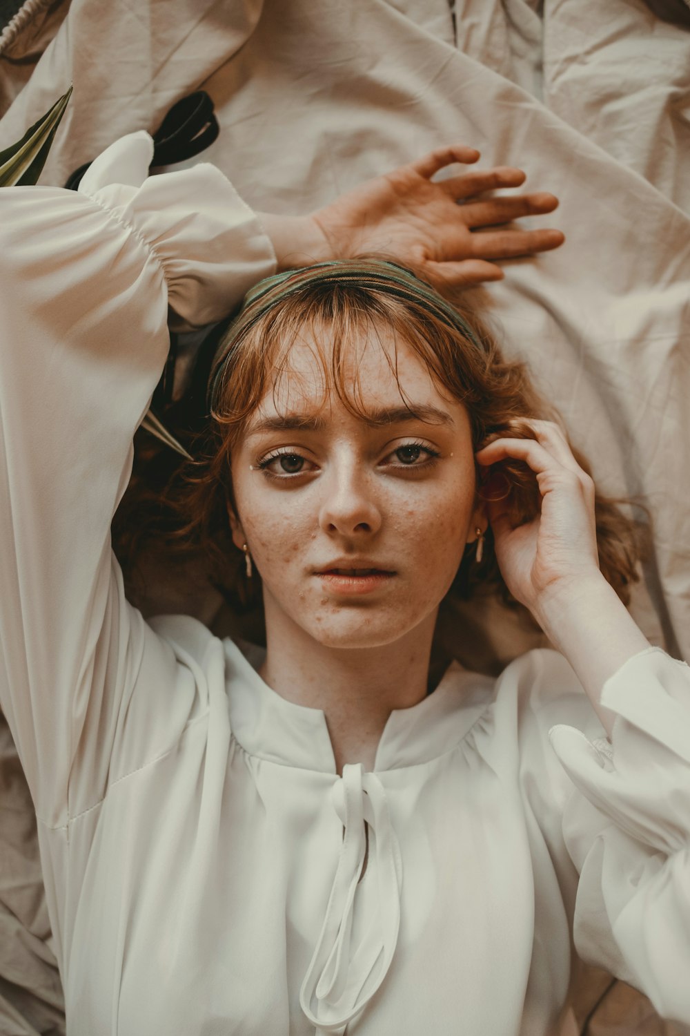 a woman laying on top of a bed with her hands on her head