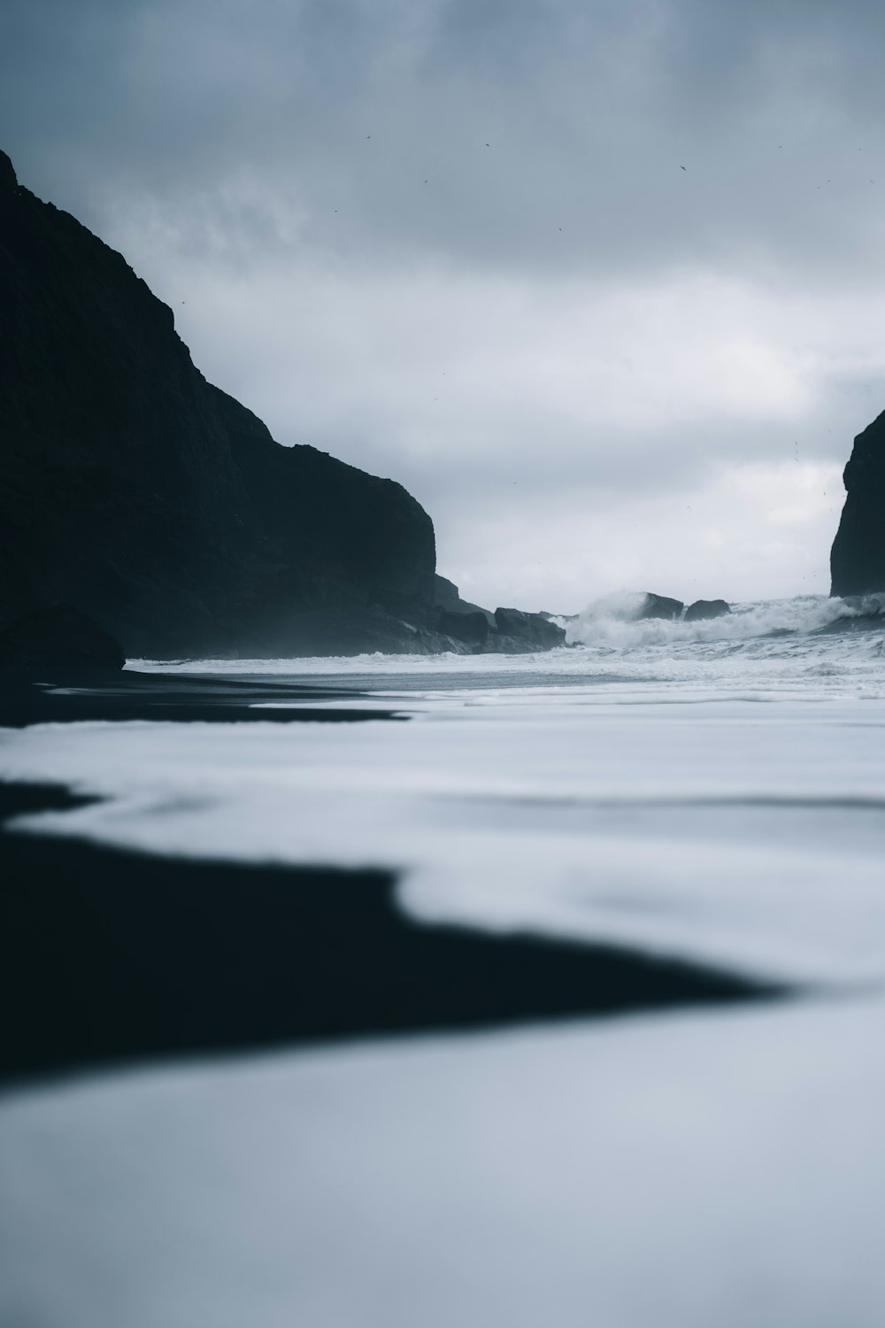 a black and white photo of the ocean and rocks