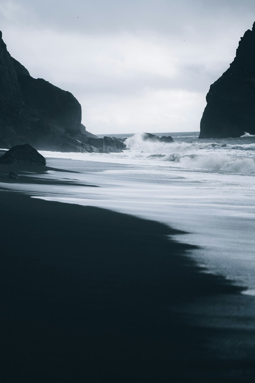 a black sand beach with waves coming in to shore