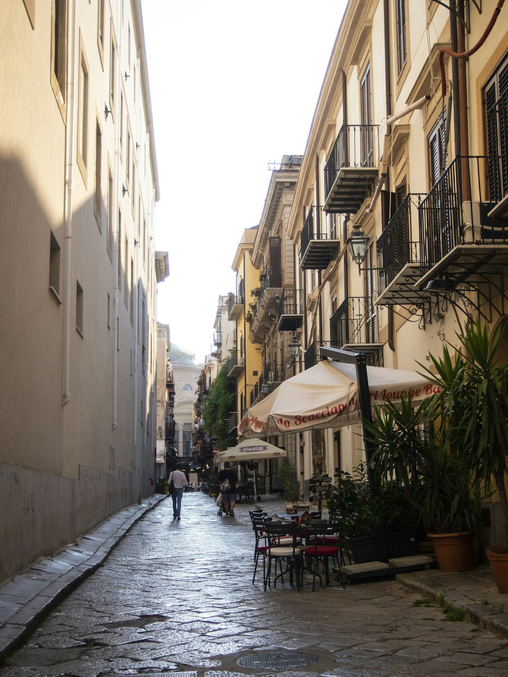 a cobblestone street lined with tables and umbrellas