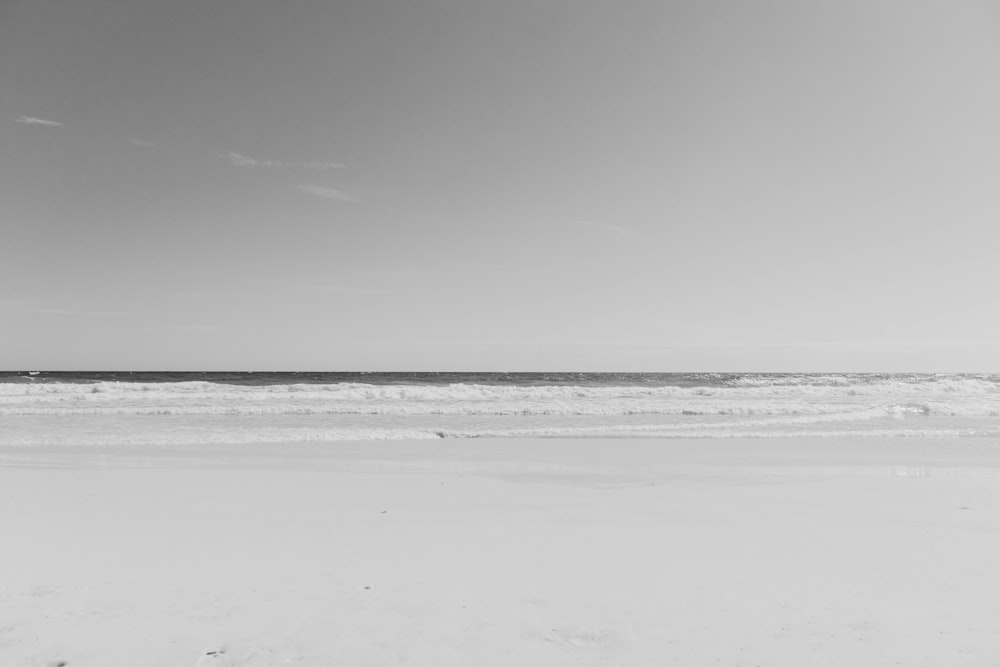 a black and white photo of a person walking on the beach