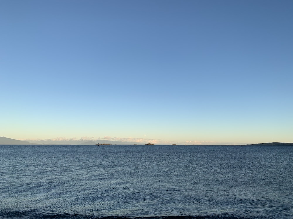 a large body of water sitting under a blue sky