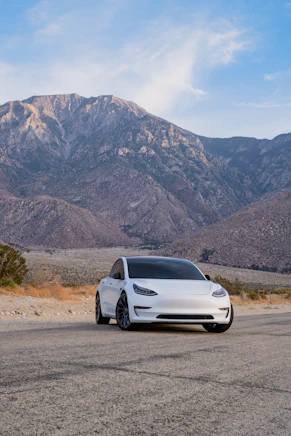 a white car parked in front of a mountain range