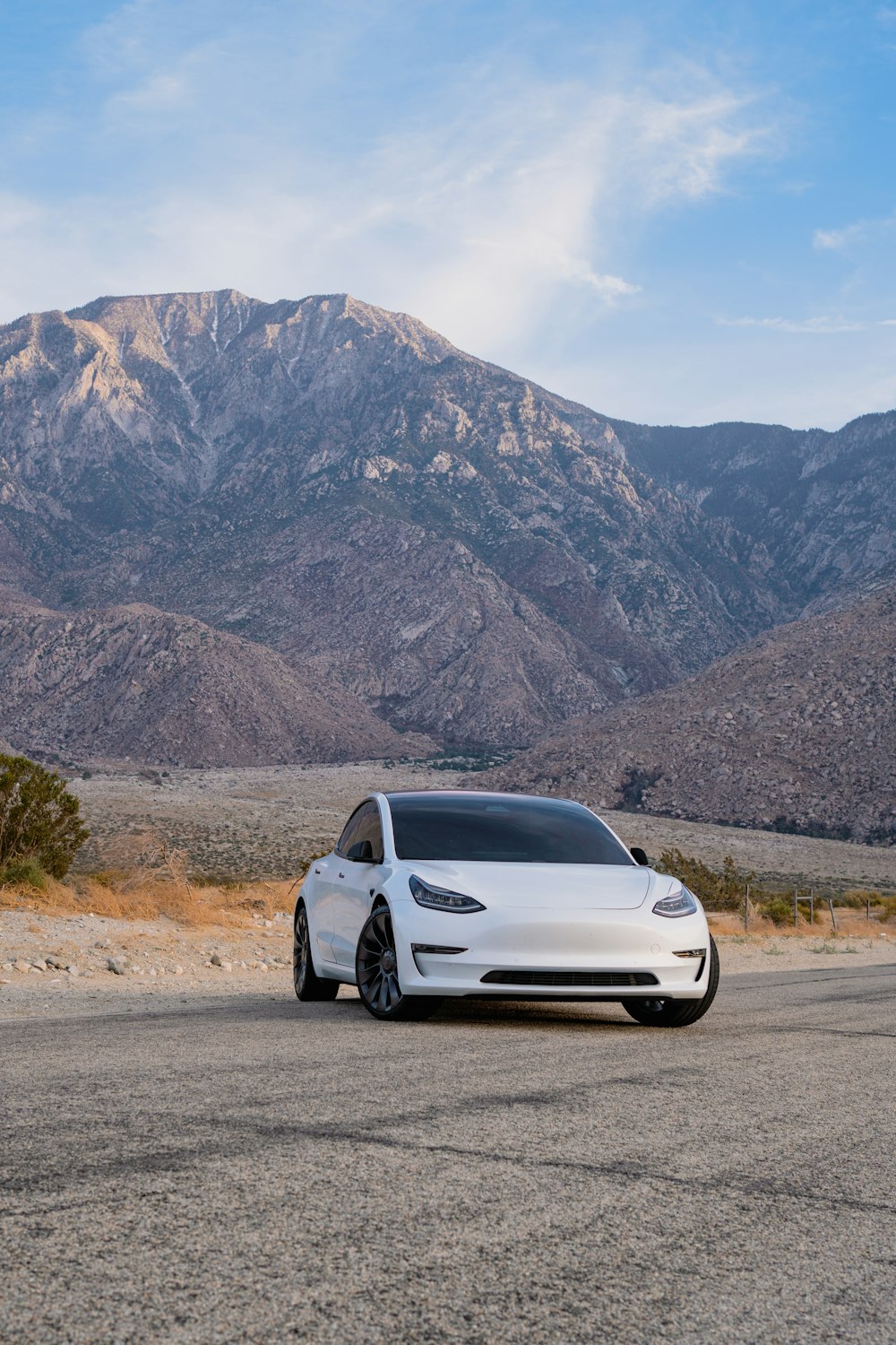 a white car parked in front of a mountain range