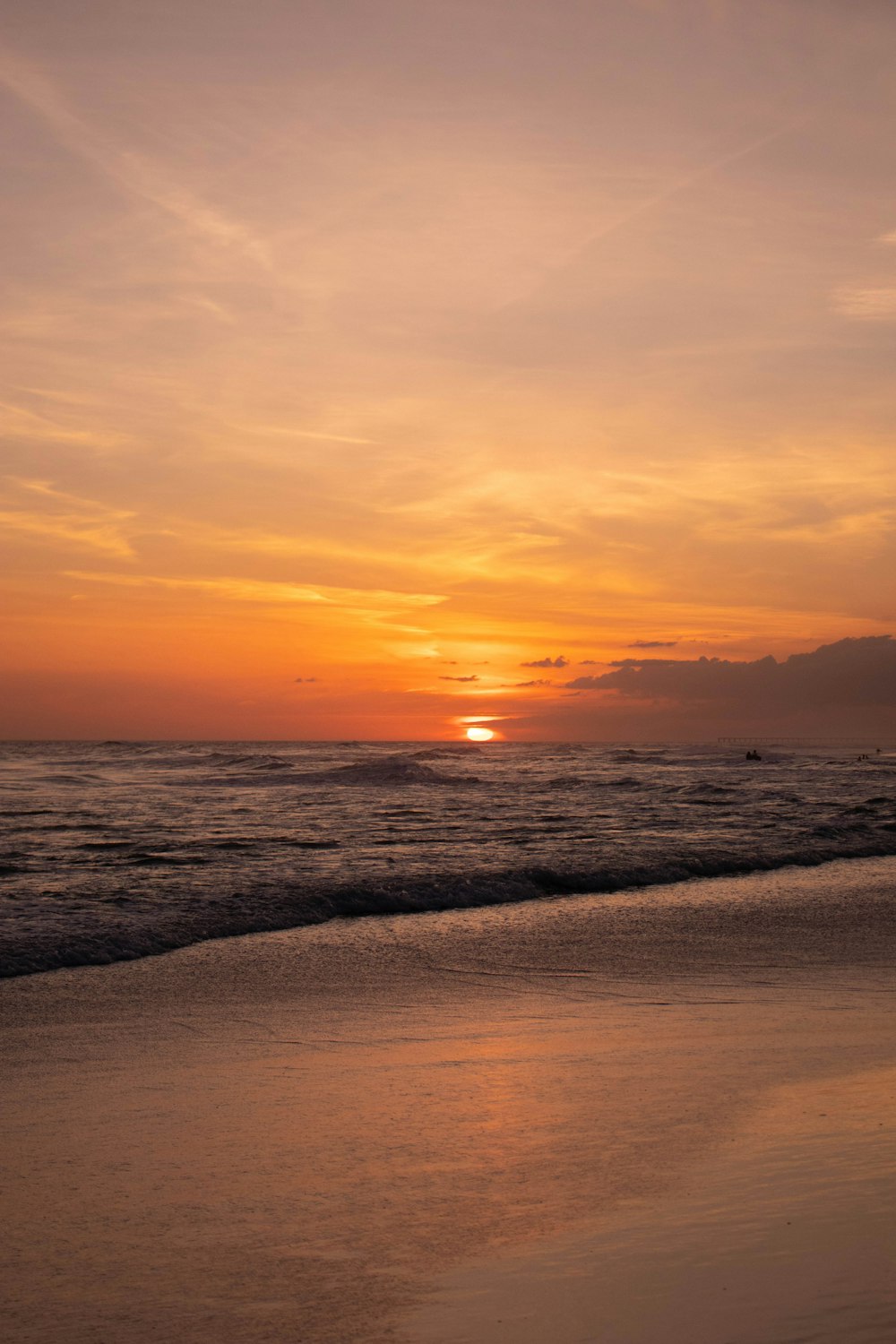 the sun is setting over the water at the beach