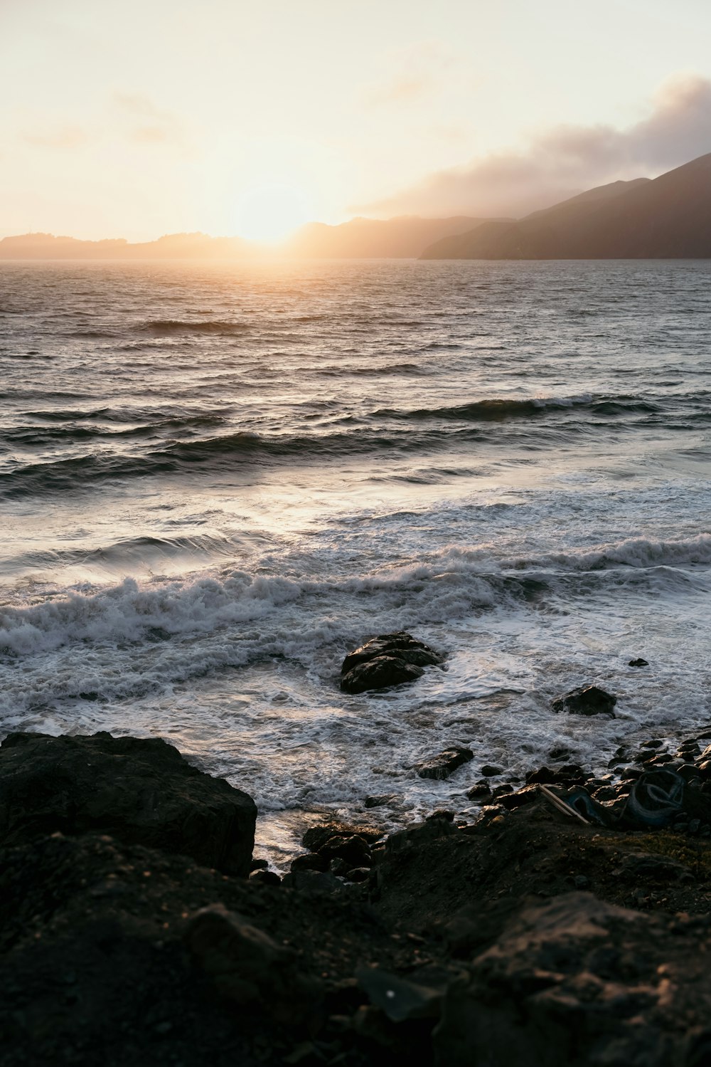 the sun is setting over the ocean with waves