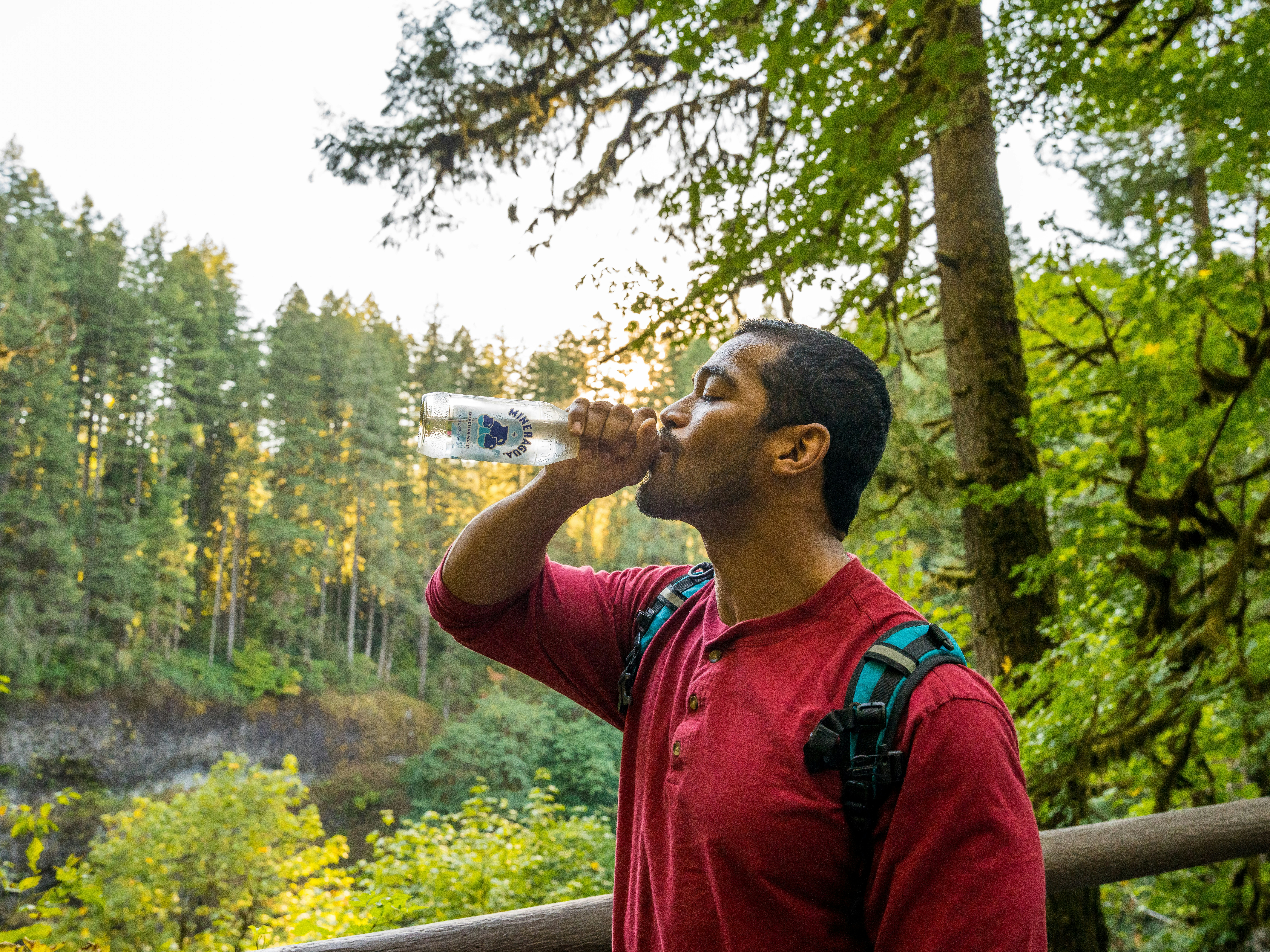a man in a red shirt drinking from a water bottle