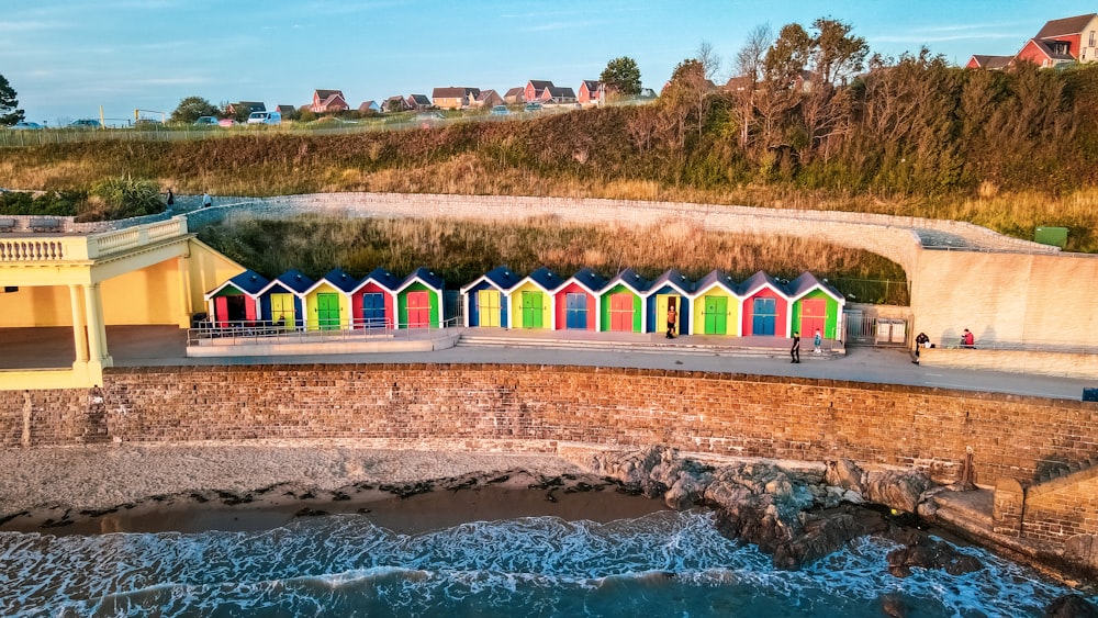 Una hilera de coloridas cabañas de playa junto a un cuerpo de agua