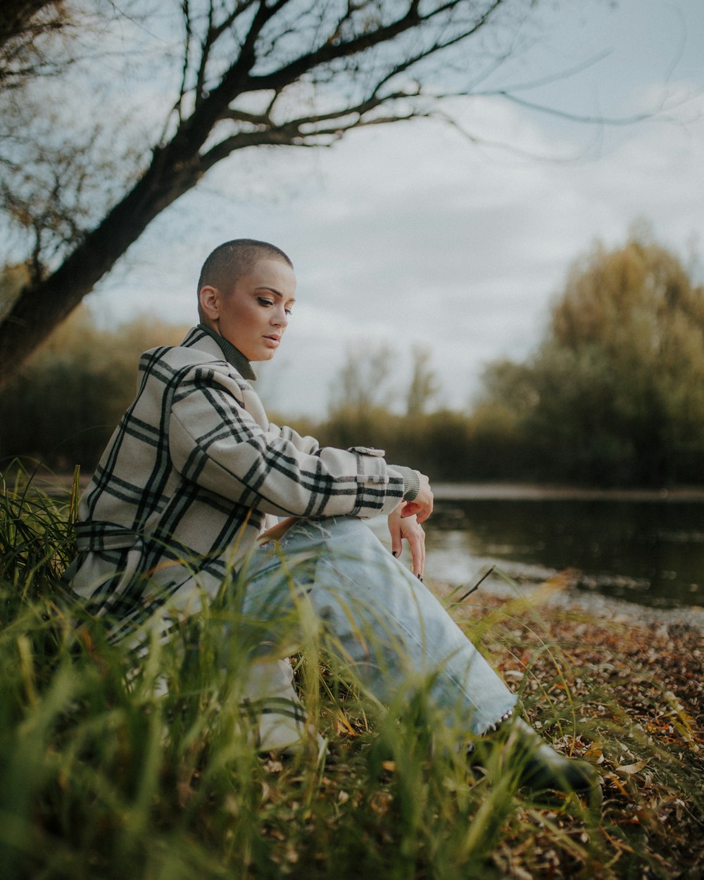 a woman sitting on the ground next to a tree