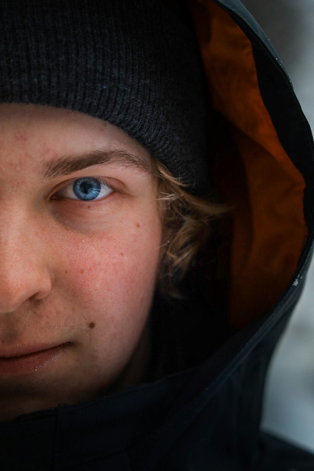 a close up of a person wearing a jacket and a beanie