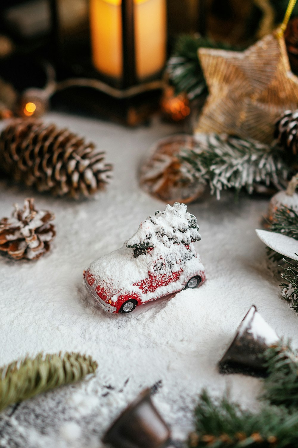 a toy car is covered in snow next to pine cones