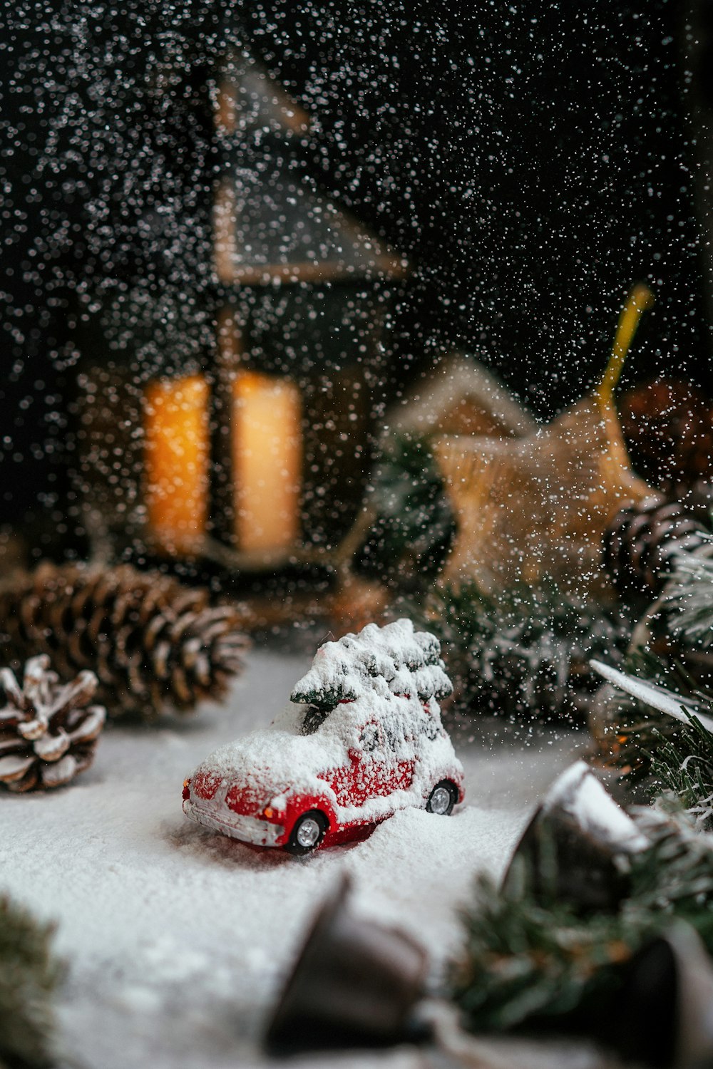 a toy car covered in snow next to a christmas tree