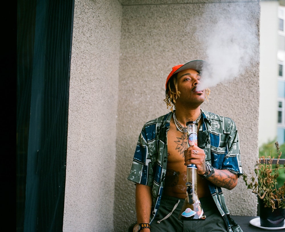 a man smoking a cigarette next to a potted plant