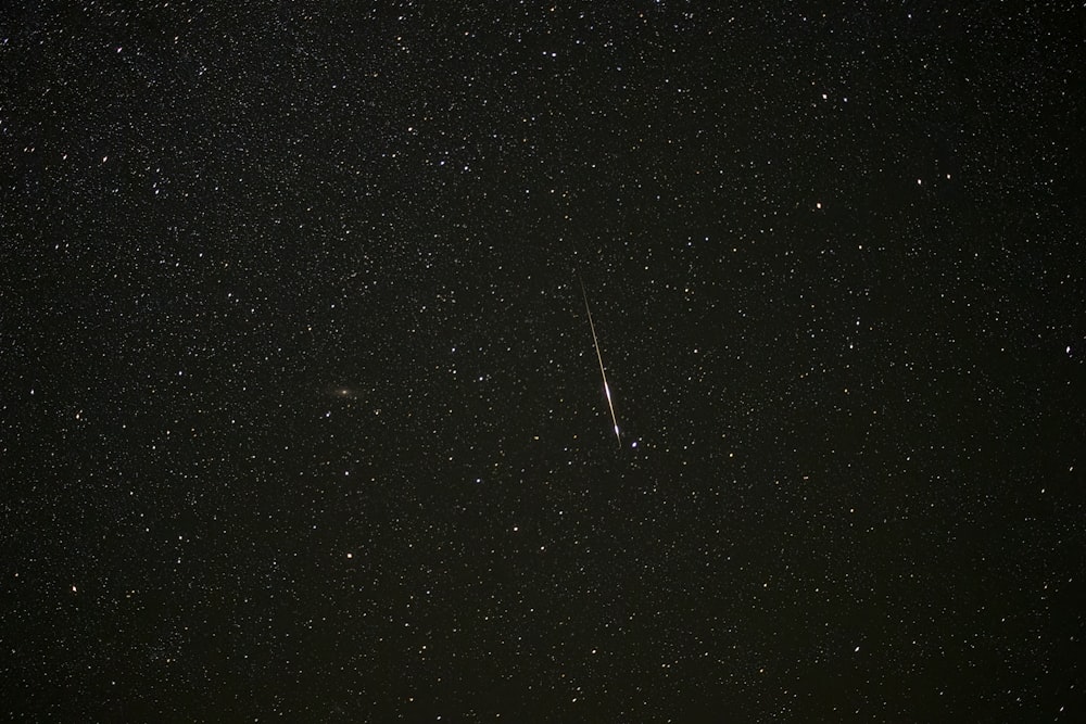 a dark sky with stars and a bright streak