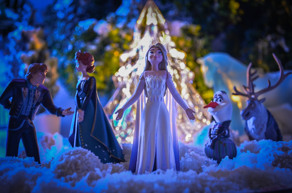 um grupo de estatuetas de brinquedo em pé em torno de uma árvore de Natal