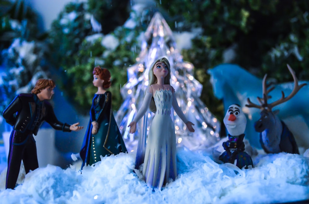 a group of figurines standing in front of a christmas tree