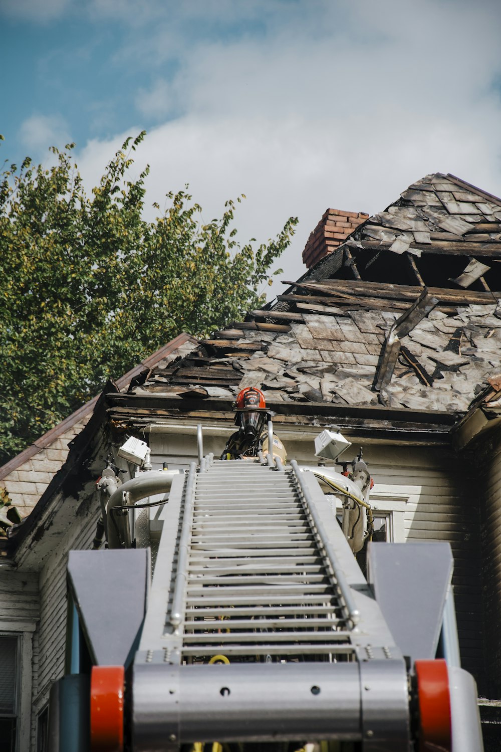 Ein Feuerwehrmann steht auf einer Leiter vor einem Haus