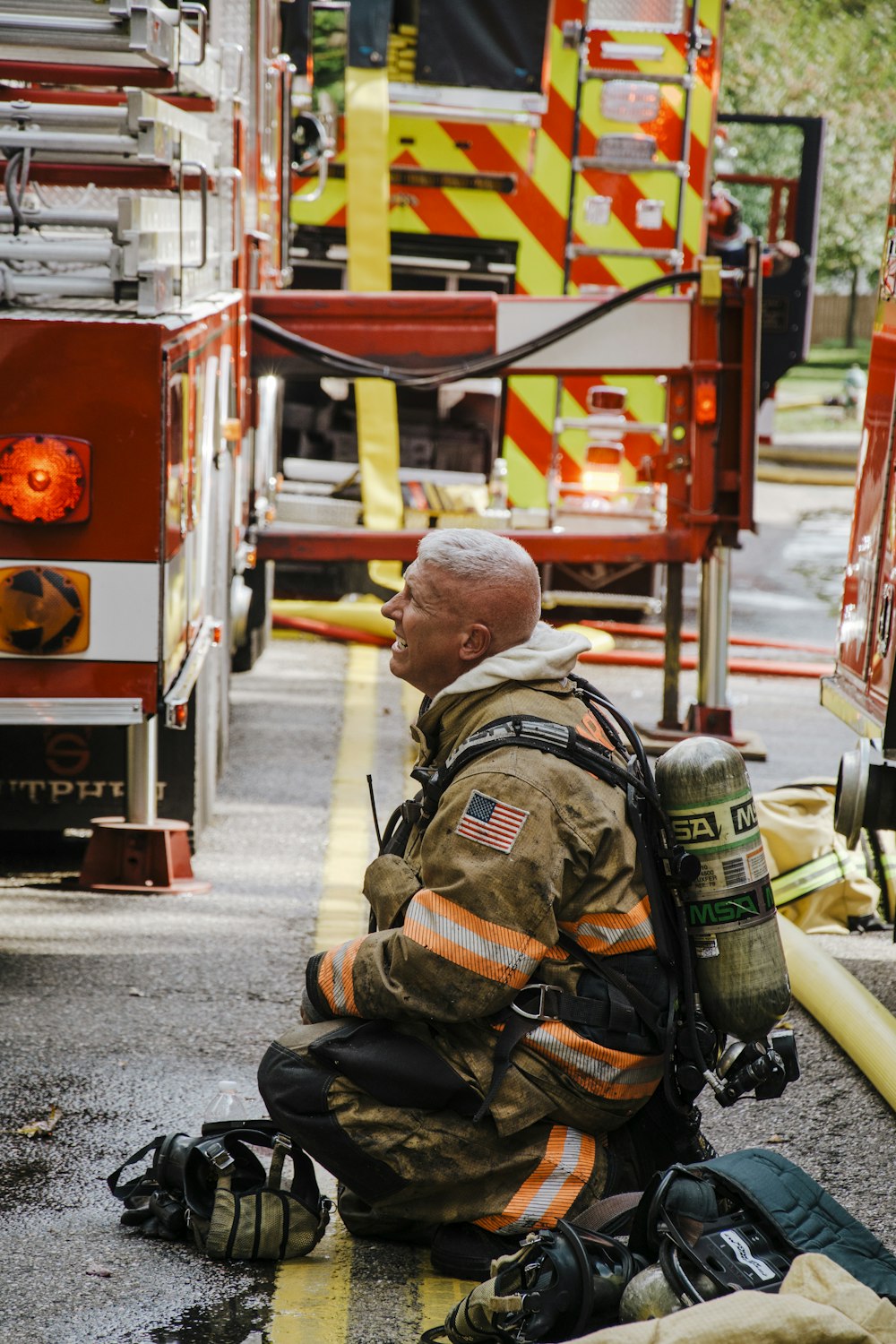 Un pompiere seduto a terra accanto a un camion dei pompieri