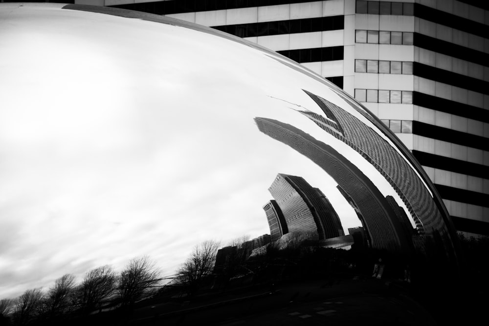 a large metal object in front of a tall building