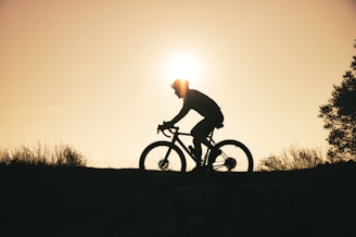 a man riding a bike down a hill at sunset